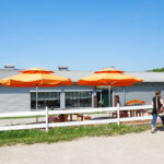 Gänsestube Eingang auf dem Gänsemarkt in Wermsdorf im Sommer mit zwei orangenen Sonnenschirmen